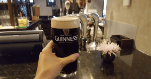 An image of a person's hand, holding a pint full of carbonated Guinness stout