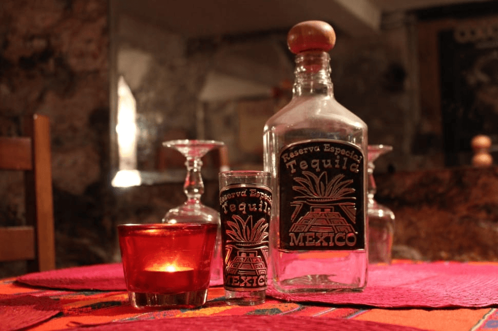 An image of a bottled tequila and a glass, set on a tabletop