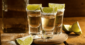 An image of three glasses filled with rich tequila, with lime and salt on top of each glass