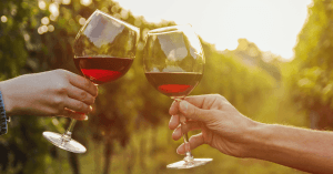An image of two clinking glasses of red wine