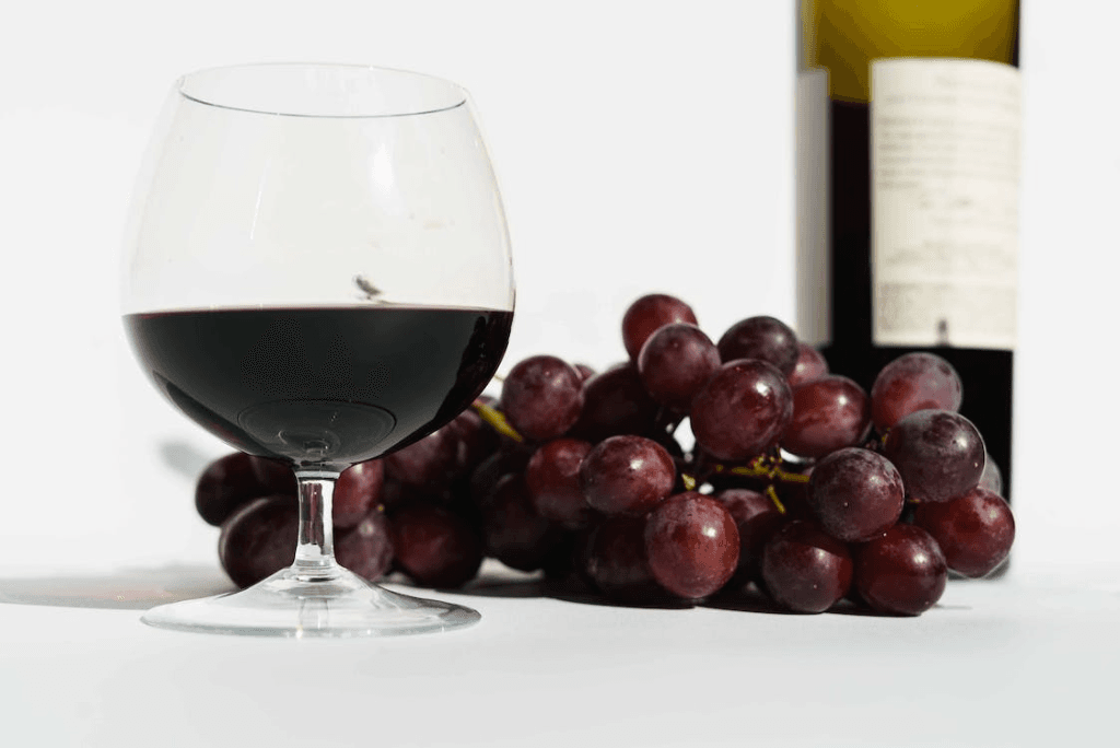 Red wine and grapes on a white table