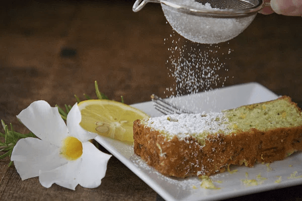 An image of sliced lemon cake with a drizzle of powdered sugar