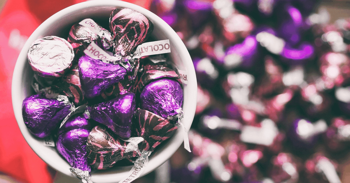 Are Hershey's Kisses Gluten-Free? An image of a cup full of Hershey's Kisses with a bunch on the background