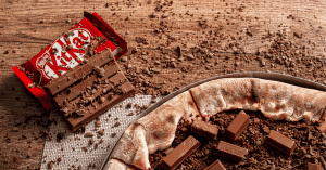 Are Kit Kats Gluten-Free? An image of KitKat Chocolate on a woody surface with shredded chocolates