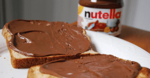 Is Nutella Gluten-Free? An image of sliced bread with Nutella spread and Nutella jar at the back