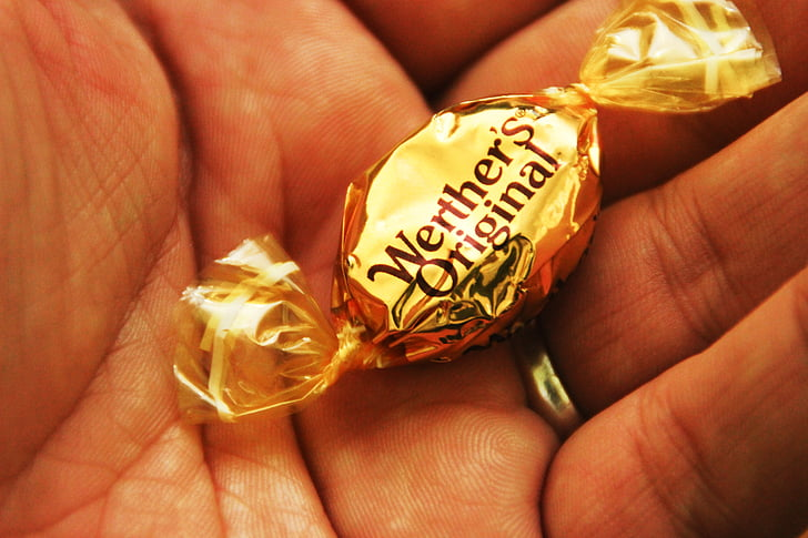 A piece of Werther's Original Candy on a person's palm
